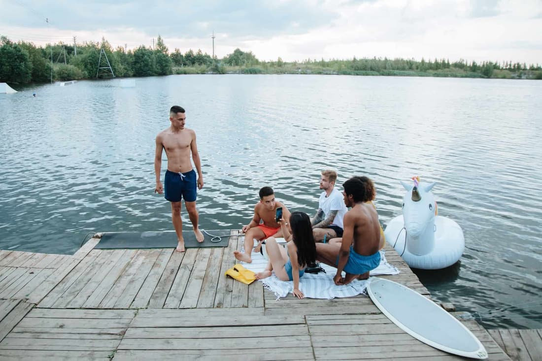 A group of friends enjoying a summer day by the lake with an inflatable unicorn