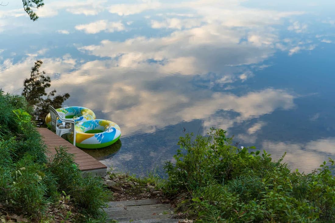 Serene lakeside view with inflatable rings and scenic reflection